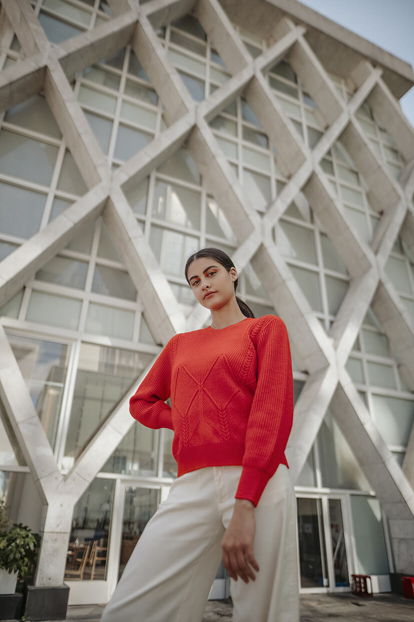 femme en pull rouge devant bâtiment La Défense Paris