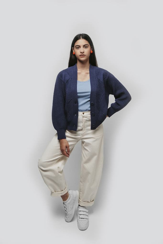 jeune femme brune portant un cardigan bleu et un pantalon blanc